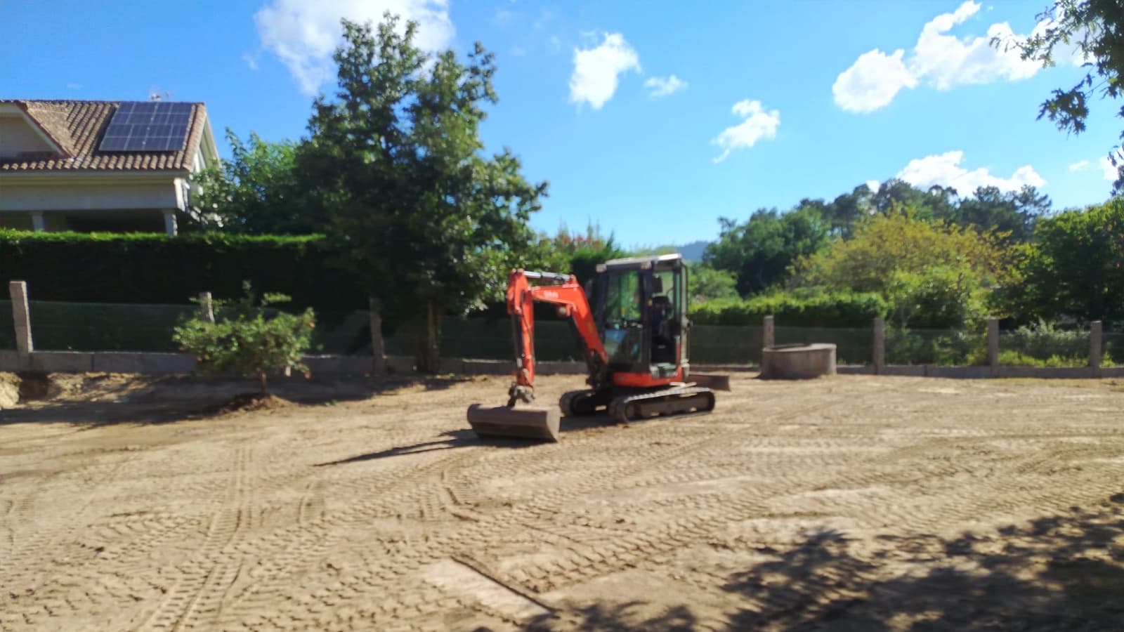 Miniexcavadora de Excavaciones Nigrán trabajando junto a una vivienda en construcción